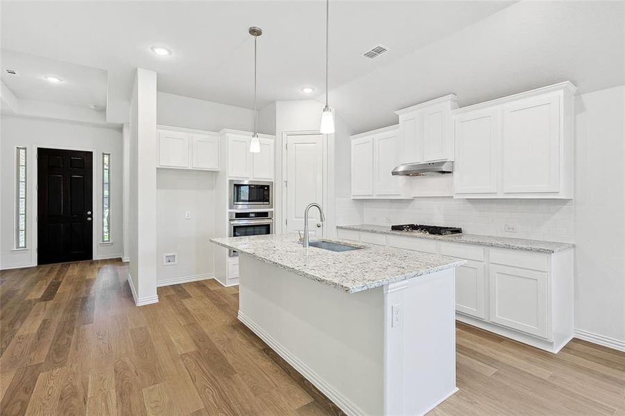 Kitchen featuring sink, white cabinets, light hardwood / wood-style flooring, a center island with sink, and appliances with stainless steel finishes