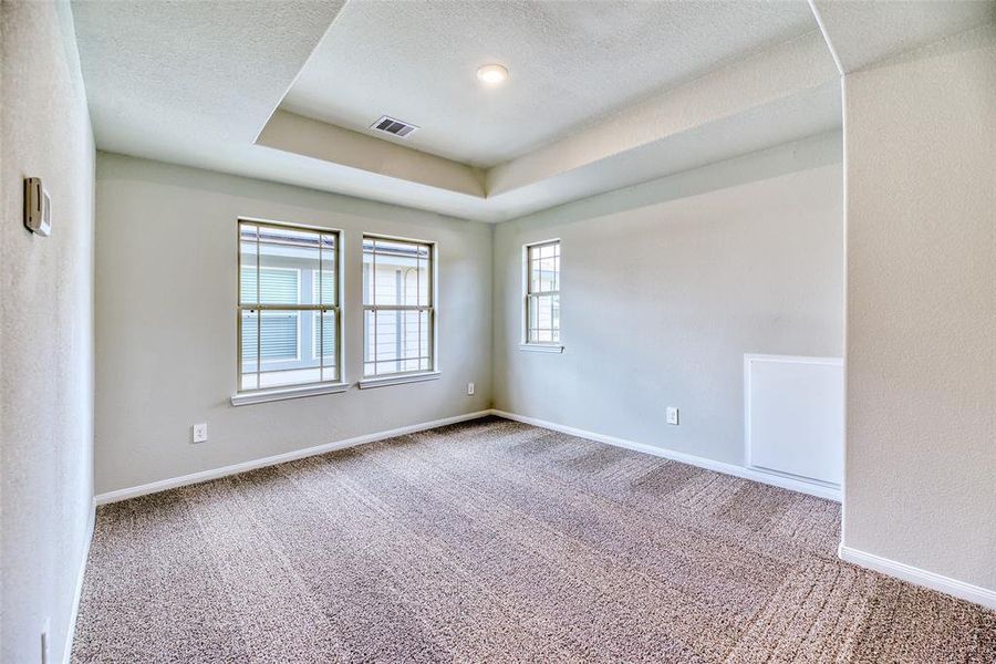 Upstairs, a spacious game room awaits, featuring an elegant tray ceiling that adds a touch of luxury to the space. Plush carpeting offers comfort underfoot, creating a cozy atmosphere. Large windows allow natural light to flood the room, enhancing its bright and inviting ambiance.