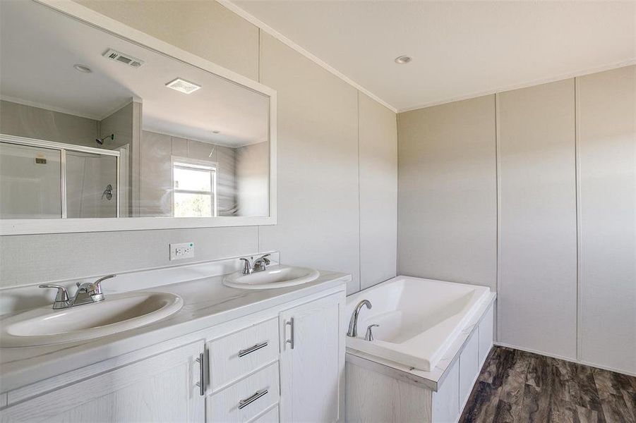 Bathroom with hardwood / wood-style floors, independent shower and bath, crown molding, and vanity