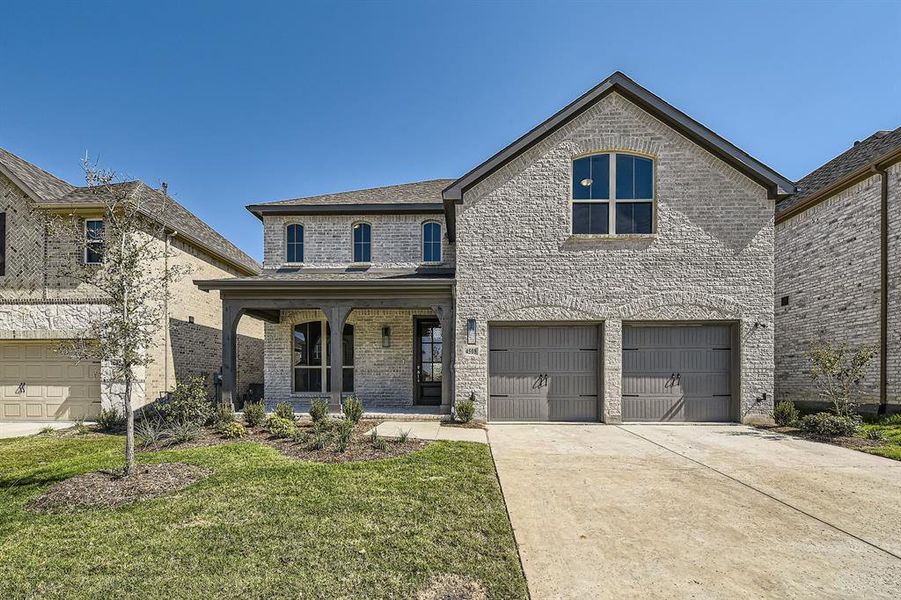 View of front of home featuring a front lawn, covered porch, and a garage