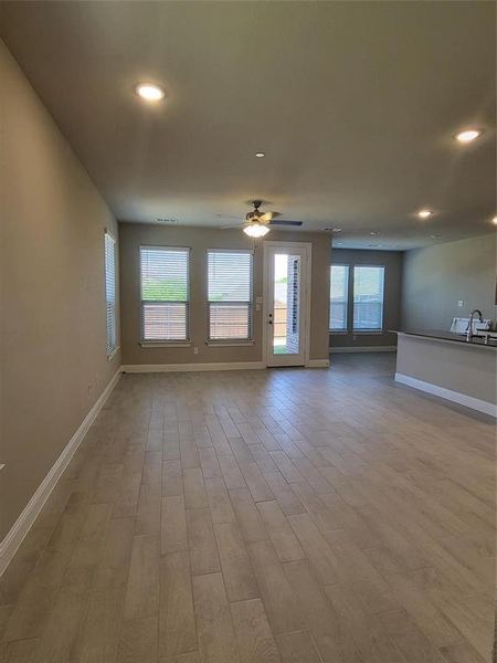 Unfurnished living room with ceiling fan, sink, and hardwood / wood-style floors