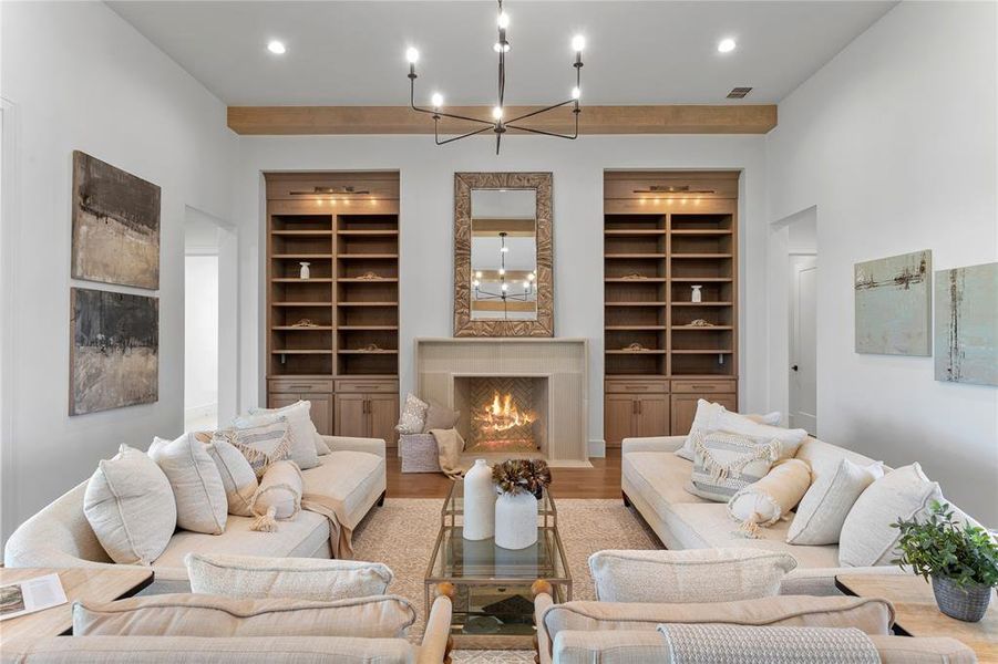 Living room features a large stone fireplace flanked with custom light white oak shelving and built in cabinetry,.