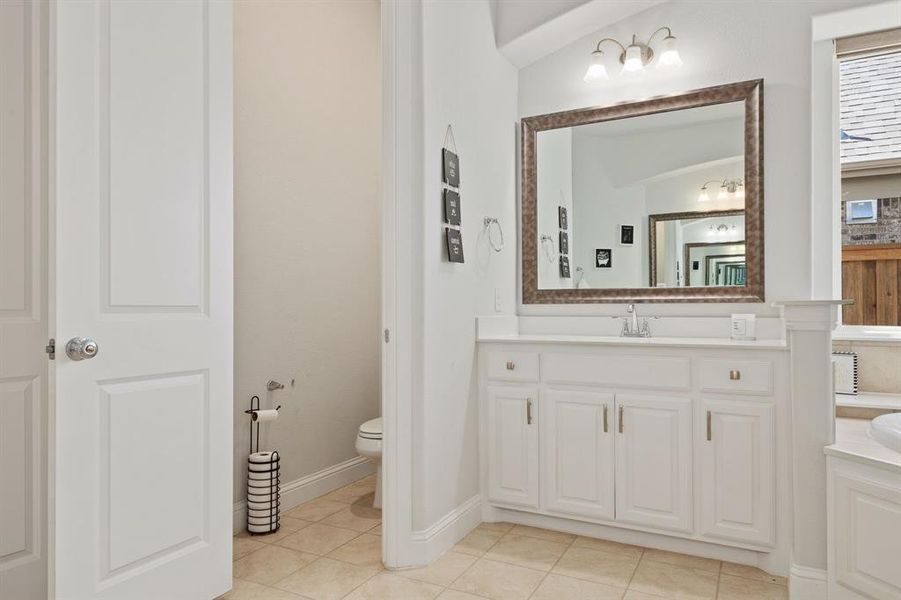 Bathroom featuring tile floors, vaulted ceiling, toilet, and vanity with extensive cabinet space