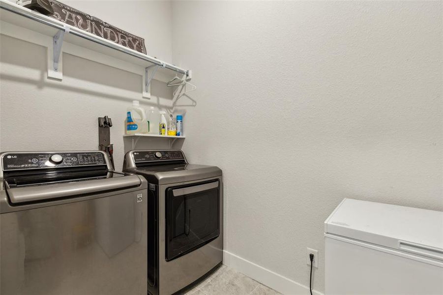 Downstairs utility room featuring light tile patterned floors with extra space for freezer or refrigerator.