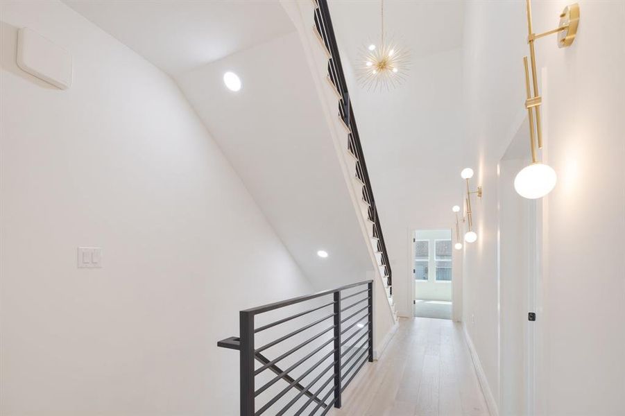 Every space in this home is exquisite.  This third floor hallway features beautiful decorative sconces and chandeliers, high ceilings, white oak floors, metal stair rail and beautiful natural light.