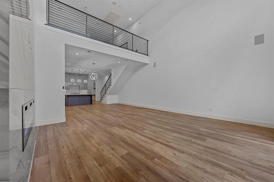 Unfurnished living room with a high ceiling and light wood-type flooring