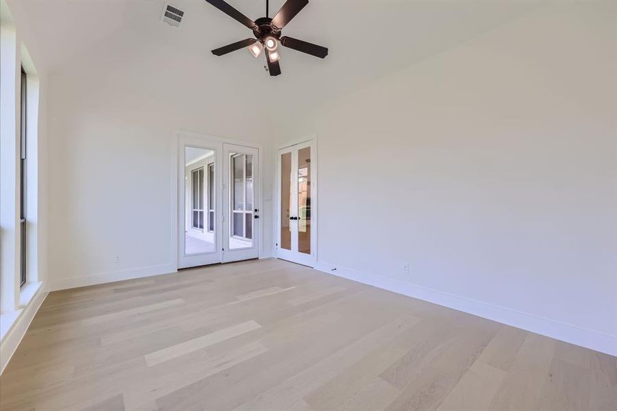 Empty room featuring french doors, vaulted ceiling, light hardwood / wood-style floors, and ceiling fan