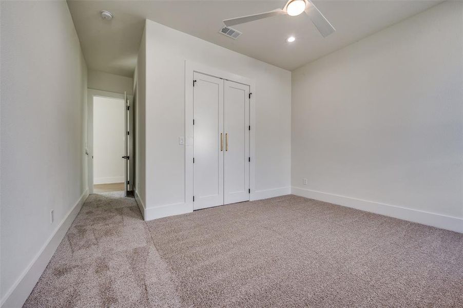 Unfurnished bedroom featuring a closet, light colored carpet, and ceiling fan