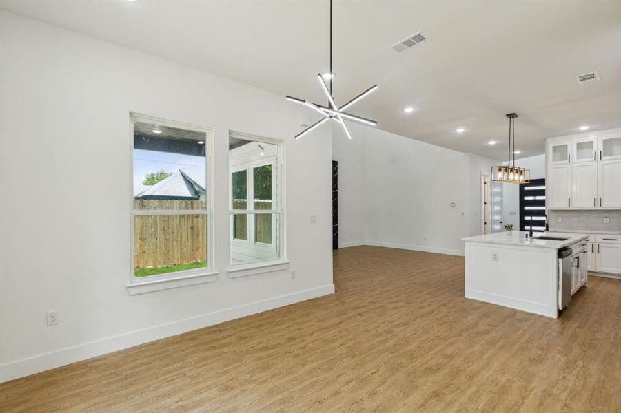 Kitchen featuring white cabinetry, a chandelier, tasteful backsplash, and light wood-type flooring