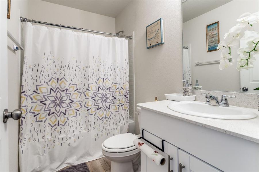 Full bathroom featuring vanity, hardwood / wood-style floors, shower / bath combo, and toilet