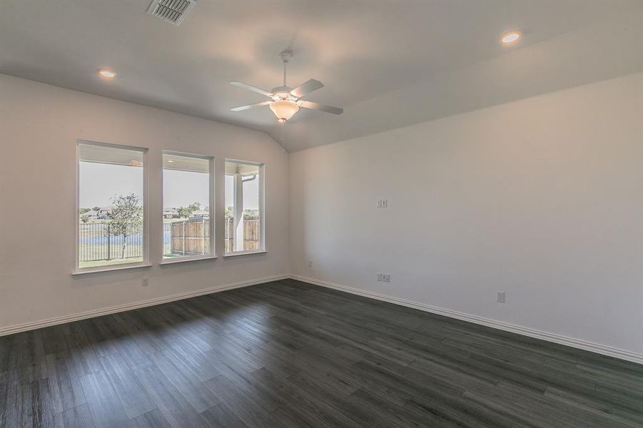 Empty room with vaulted ceiling, ceiling fan, and dark wood-type flooring