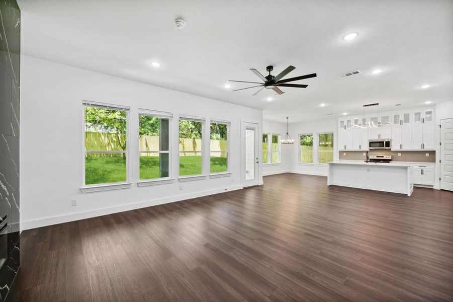 Unfurnished living room featuring a wealth of natural light, dark hardwood / wood-style flooring, and ceiling fan