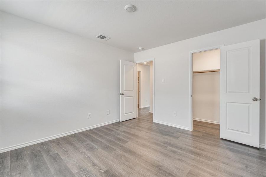 Unfurnished bedroom featuring light hardwood / wood-style flooring, a closet, and a walk in closet