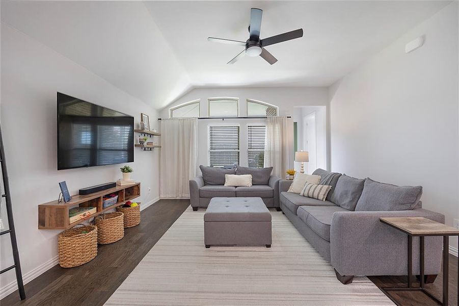 Living room with lofted ceiling, hardwood / wood-style floors, and ceiling fan