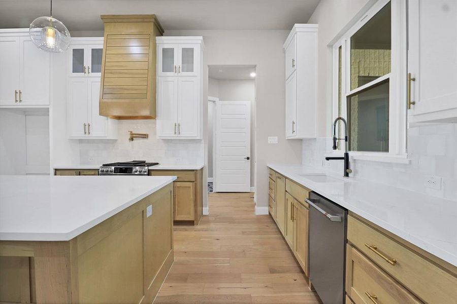 Kitchen featuring light hardwood / wood-style flooring, decorative light fixtures, sink, white cabinets, and appliances with stainless steel finishes