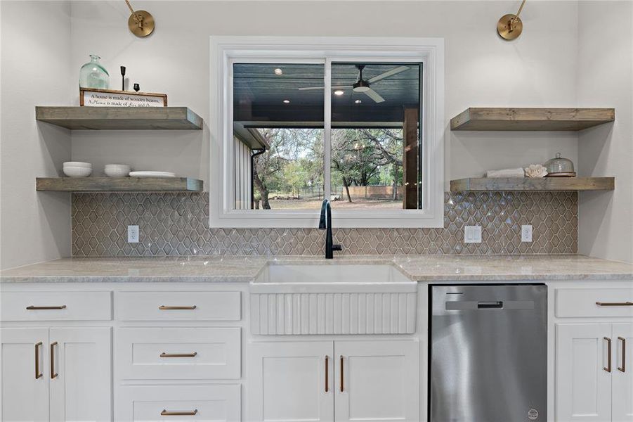 Kitchen featuring decorative backsplash, stainless steel dishwasher, and white cabinets