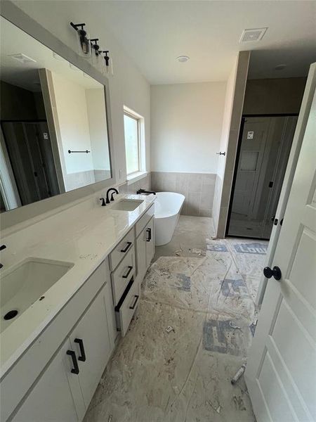 Bathroom featuring double vanity, shower with separate bathtub, and tile floors