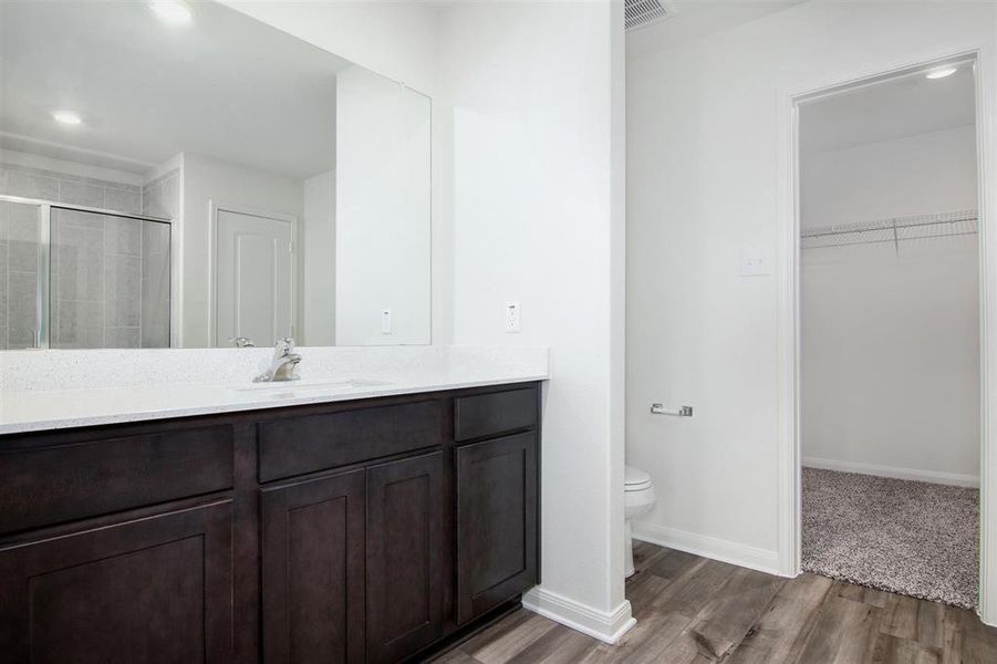 Bathroom featuring a shower with shower door, toilet, vanity, and hardwood / wood-style flooring