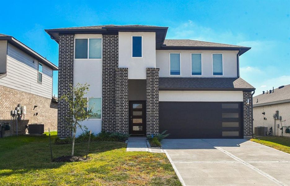 Shows the exterior of a modern, two-story home with a clean front yard.