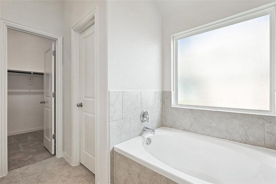 Bathroom with tiled tub and tile patterned floors