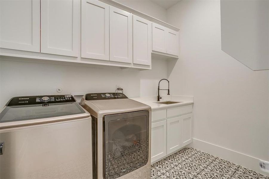 Washroom featuring sink, cabinets, washer and clothes dryer, and light tile patterned floors