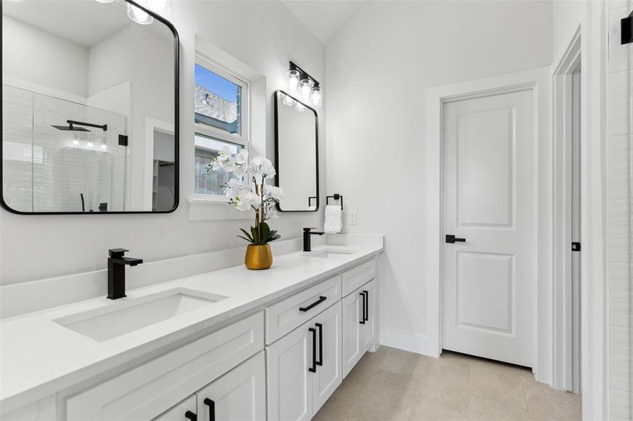 Bathroom featuring tile patterned flooring, a tile shower, and vanity