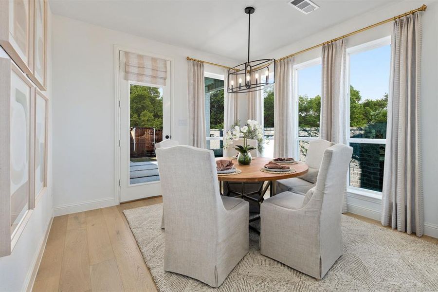 Dining area with light hardwood / wood-style flooring, a notable chandelier, and plenty of natural light