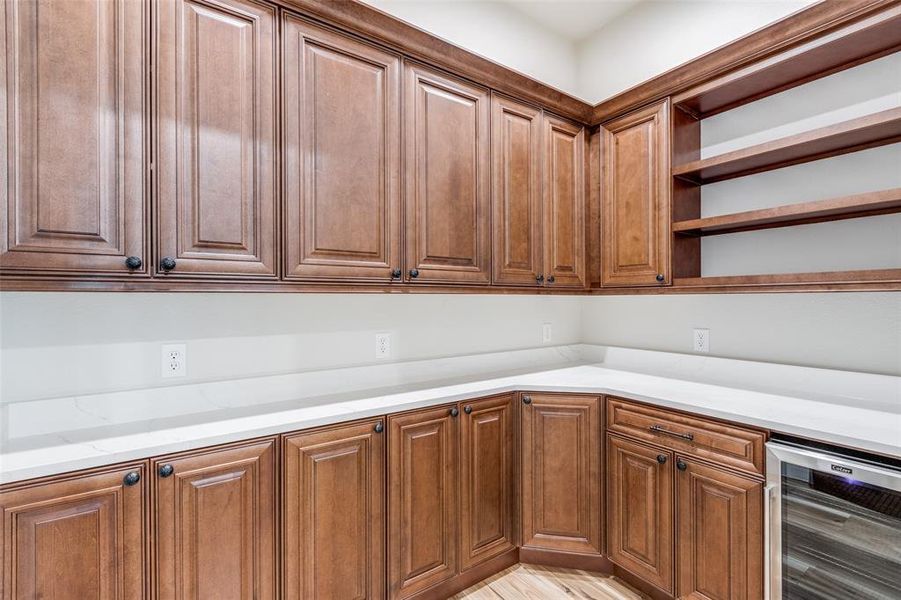 large pantry featuring quartz countertops, wine cooler, and luxury vinyl wood-style floors
