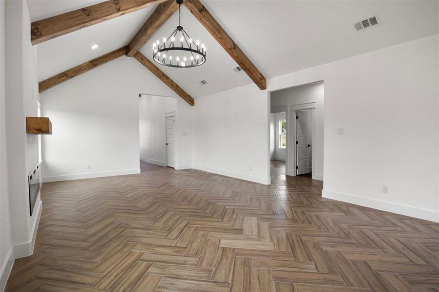 Unfurnished living room featuring vaulted ceiling with beams, a notable chandelier, and dark parquet flooring