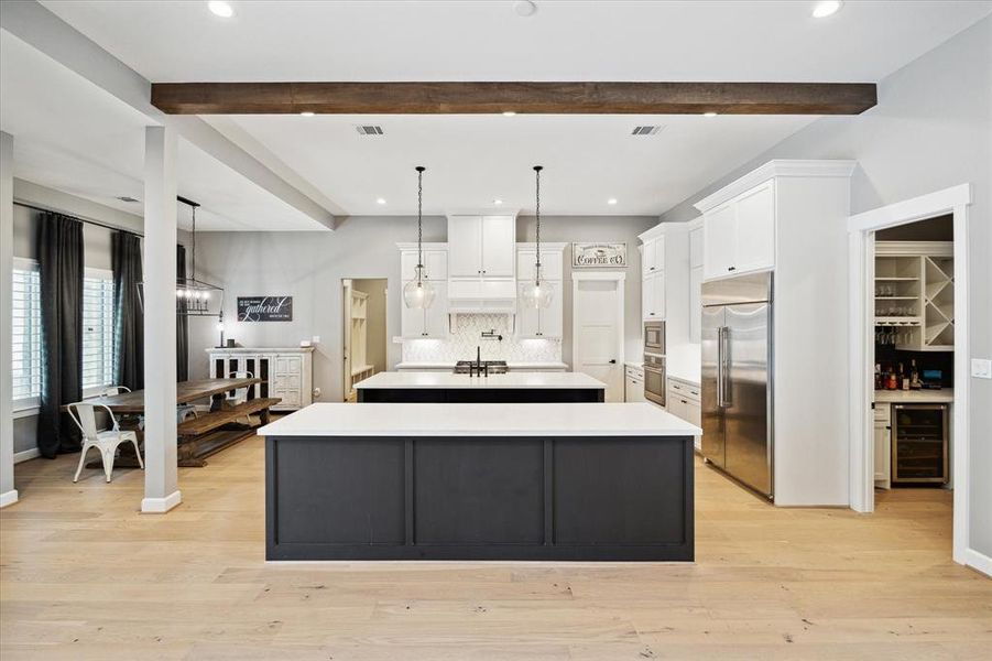 Kitchen with engineered wood floors, recessed lighting, pendant lighting and wood beam.