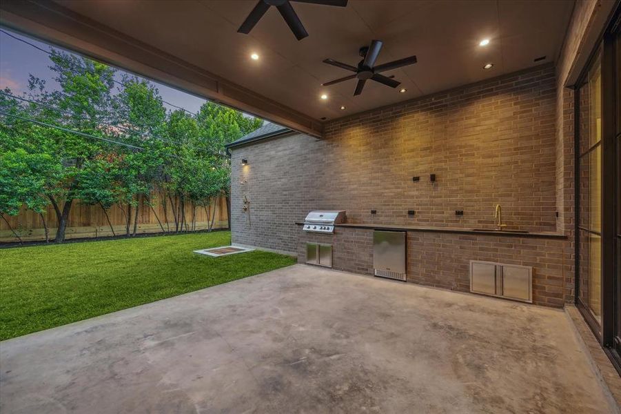 This spacious covered patio with a built-in outdoor kitchen, grill, and sink is perfect for entertaining. Overhead fans and recessed lighting provide comfort and style for gatherings in any season.