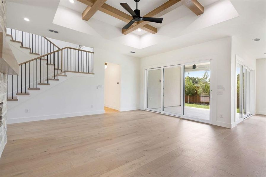 Unfurnished living room with light hardwood / wood-style flooring, beam ceiling, ceiling fan, and coffered ceiling