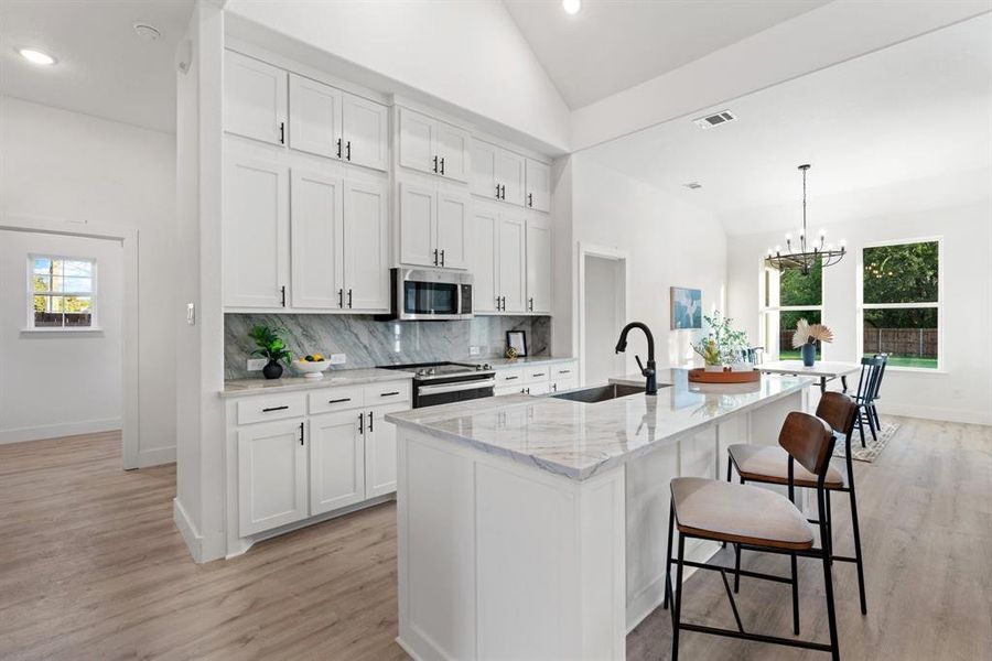 Kitchen featuring white cabinets, an island with sink, appliances with stainless steel finishes, and sink