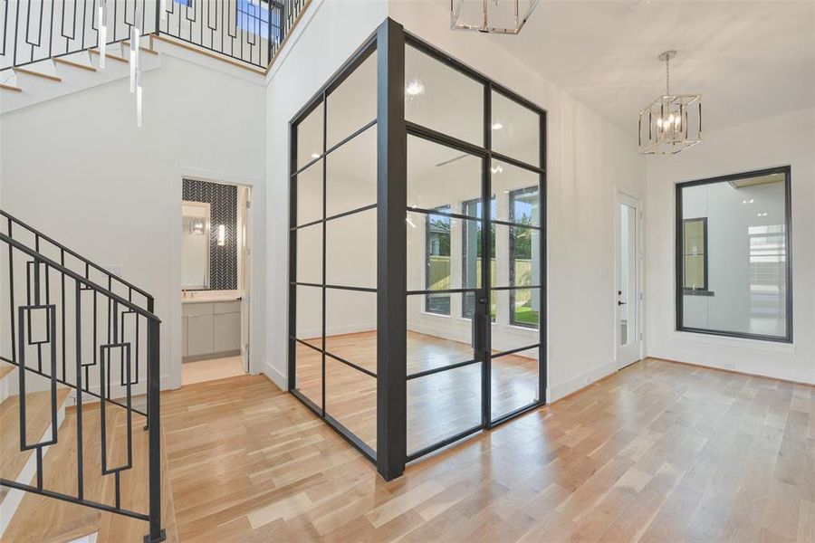 The custom corner wall of windows at the study is a focal point and allows light to flow seamlessly from the two story entry into the study and from the courtyard and lanai into the entry.