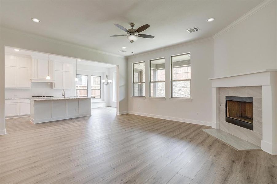 Unfurnished living room with a fireplace, ornamental molding, light wood-type flooring, and ceiling fan