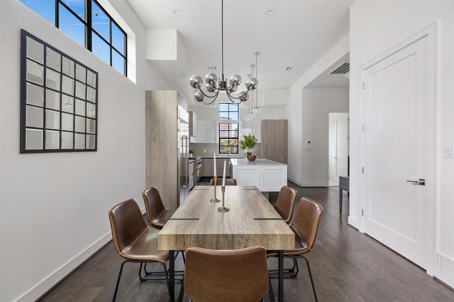 The dining area is a charming enclave of natural light and intimacy with a chic designer light fixture. Enjoy your meals in a serene atmosphere while still being connected to the larger living space.