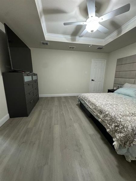 Bedroom featuring crown molding, ceiling fan, a tray ceiling, and hardwood / wood-style floors