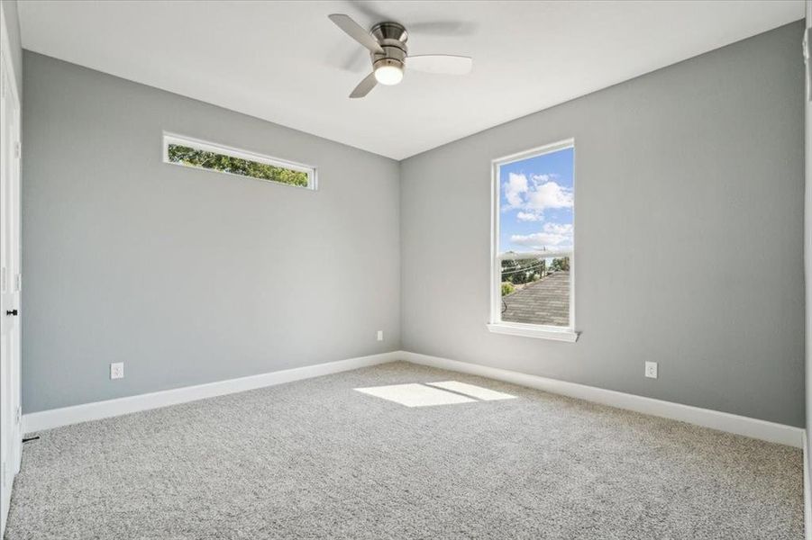 Carpeted spare room featuring ceiling fan and a healthy amount of sunlight