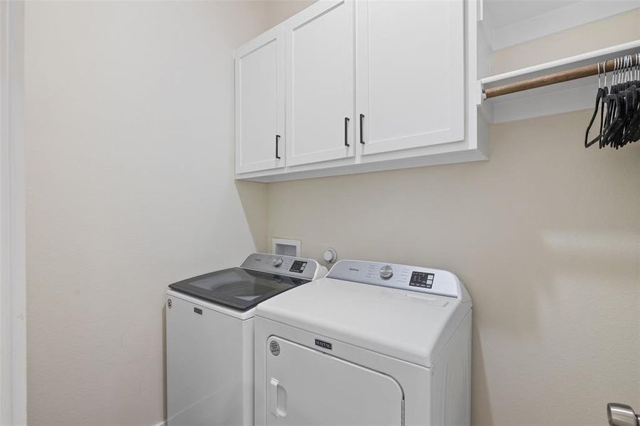 Clothes washing area featuring cabinets and washer and dryer