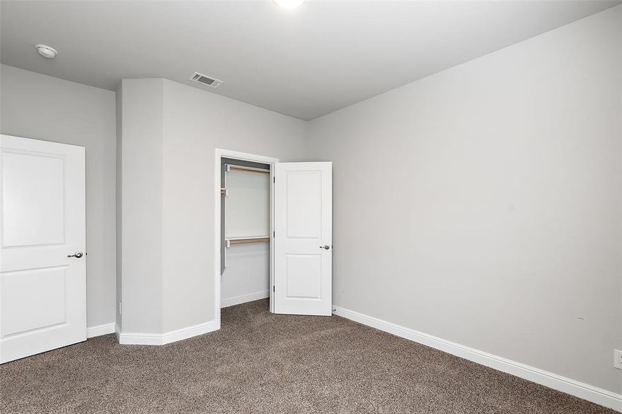 Unfurnished bedroom with dark colored carpet and a closet