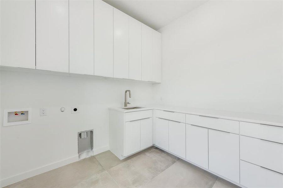 Clothes washing area with cabinets, hookup for an electric dryer, washer hookup, sink, and hookup for a gas dryer