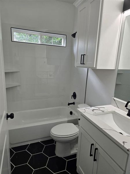 Full bathroom with vanity, tiled shower / bath combo, toilet, and a wealth of natural light