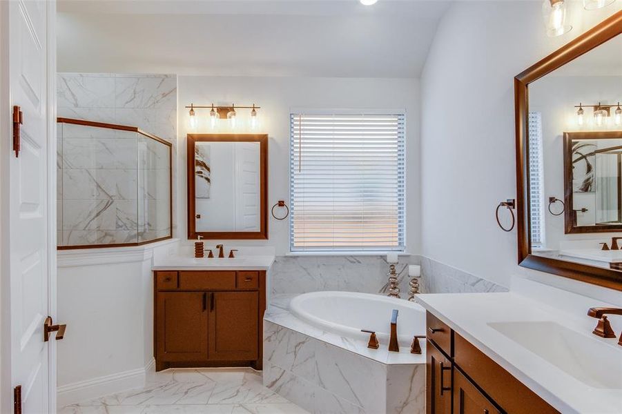 Bathroom featuring tiled bath, double sink vanity, and tile floors