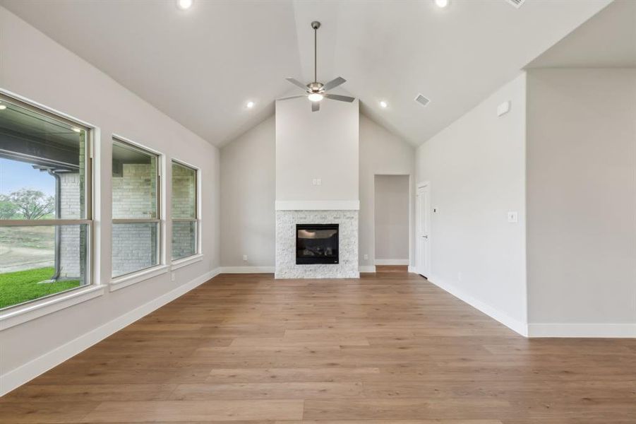 Unfurnished living room with light hardwood / wood-style floors, ceiling fan, and high vaulted ceiling