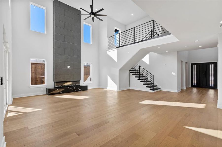 Unfurnished living room featuring a high ceiling, light hardwood / wood-style floors, and ceiling fan