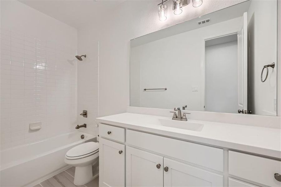 Full bathroom featuring vanity, toilet, and tiled shower / bath combo