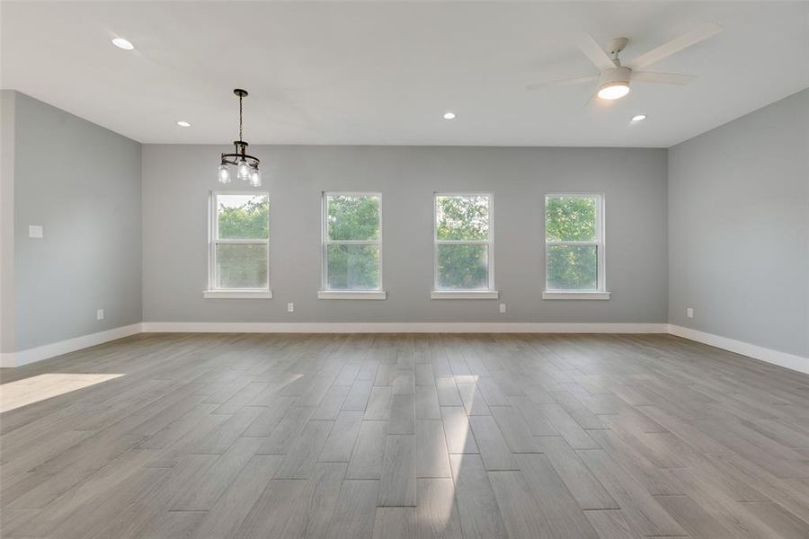 Empty room featuring light hardwood / wood-style floors and ceiling fan with notable chandelier