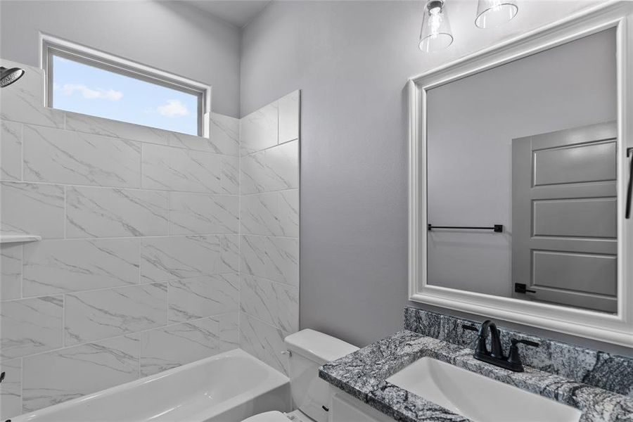 Full bathroom featuring vanity, tiled shower / bath combo, and toilet