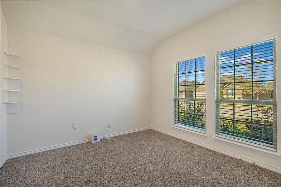 Carpeted spare room featuring lofted ceiling