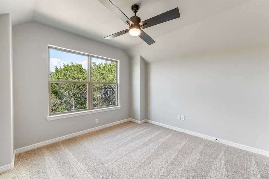 Spare room featuring carpet floors, lofted ceiling, and ceiling fan